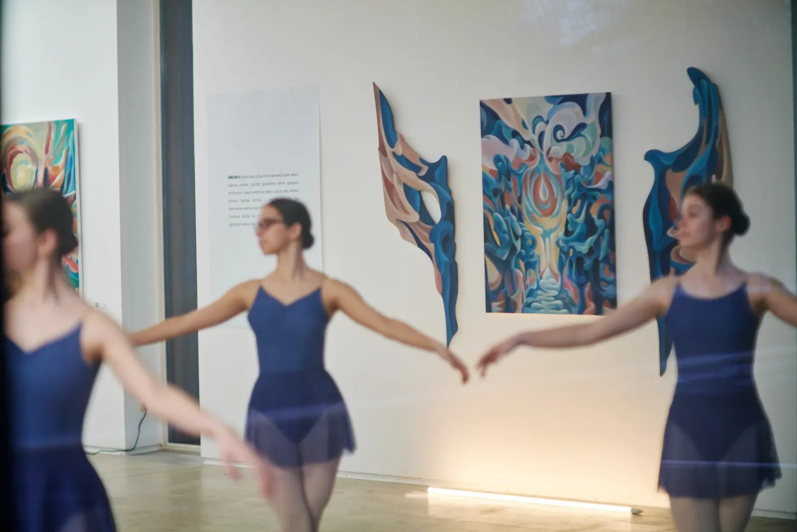 Dancers performing in front of paintings at Dimension of the Heart