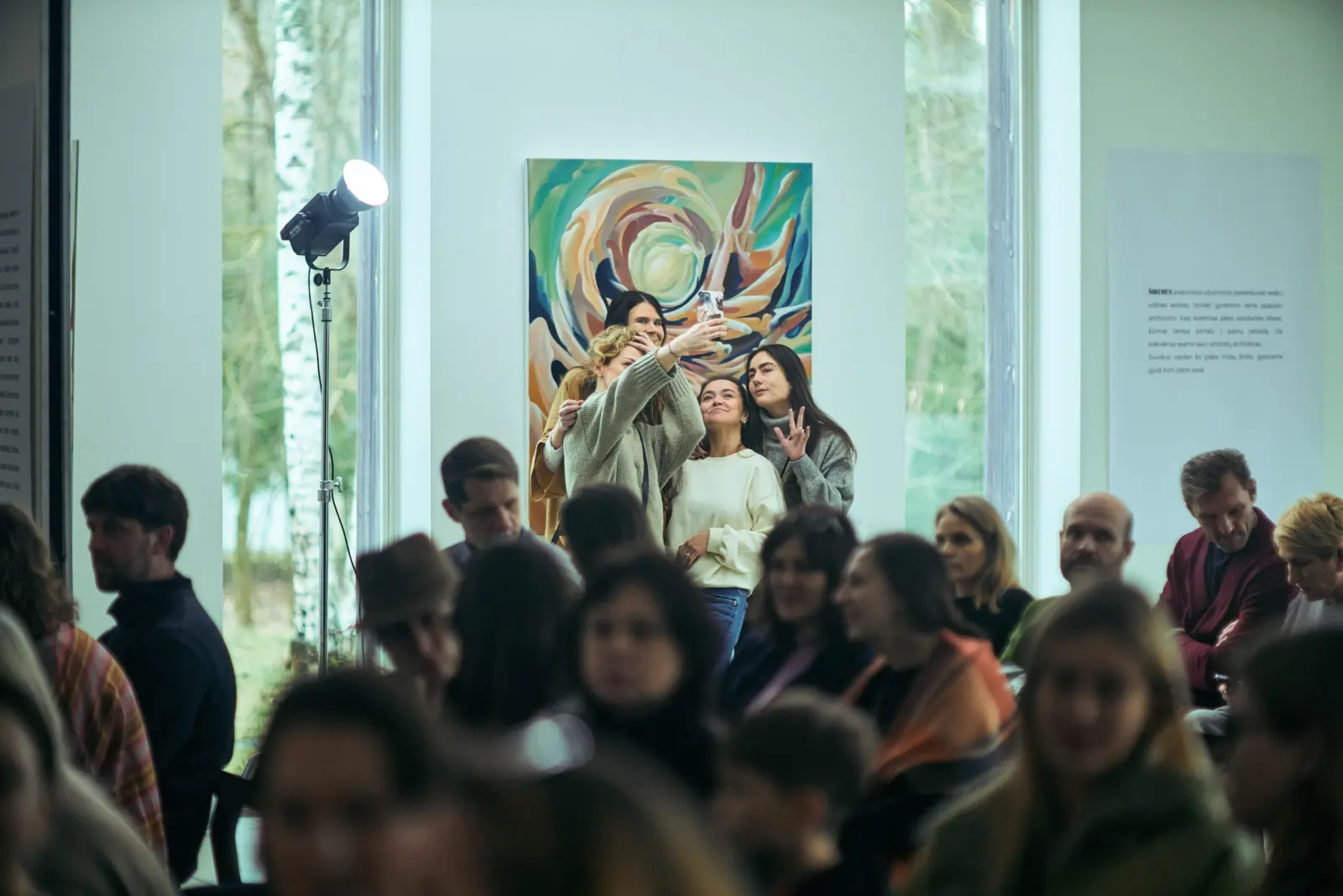 Audience seated beneath paintings at Dimension of the Heart