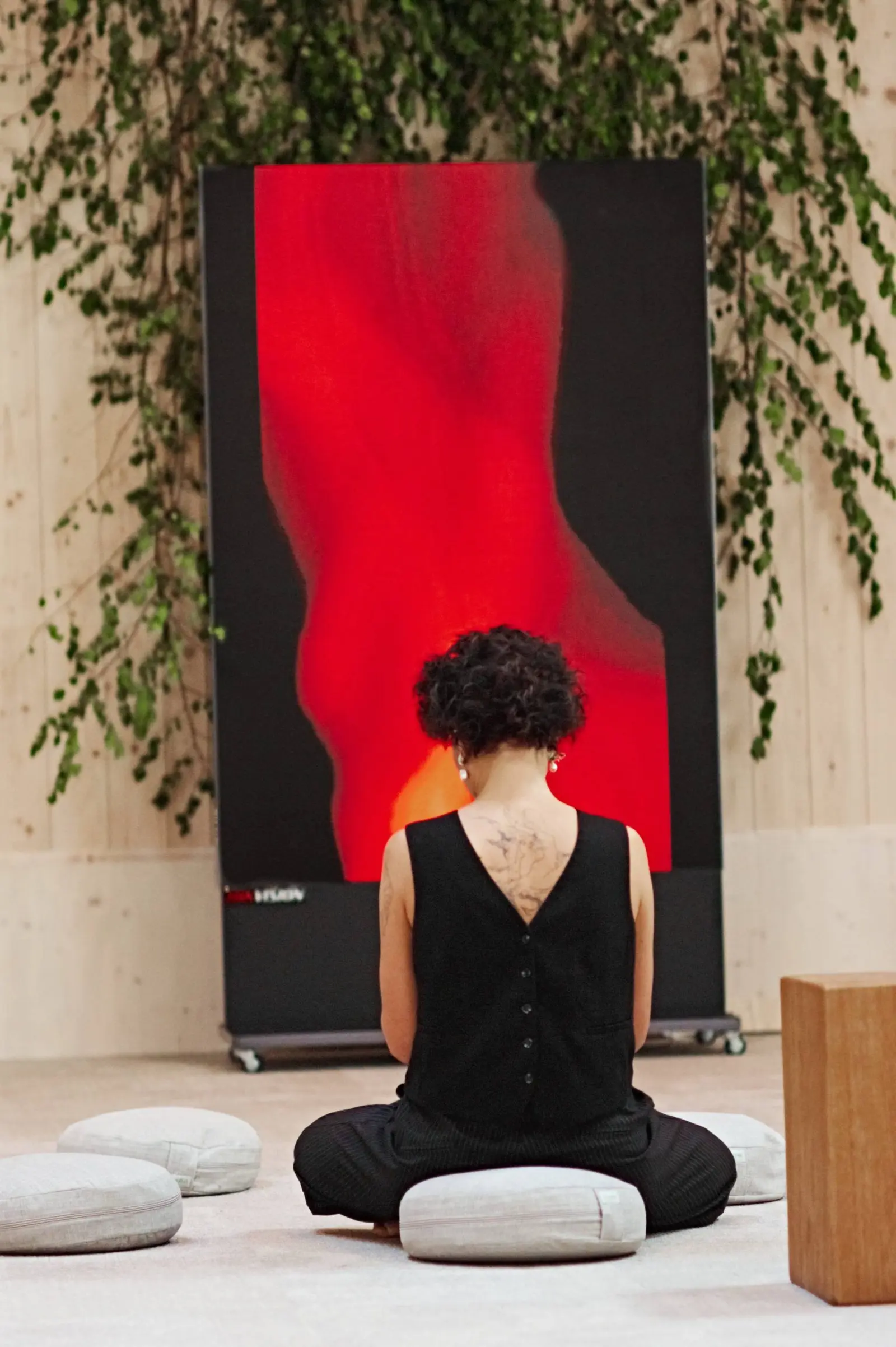 A visitor seated in front of a red painting at Nuoramos