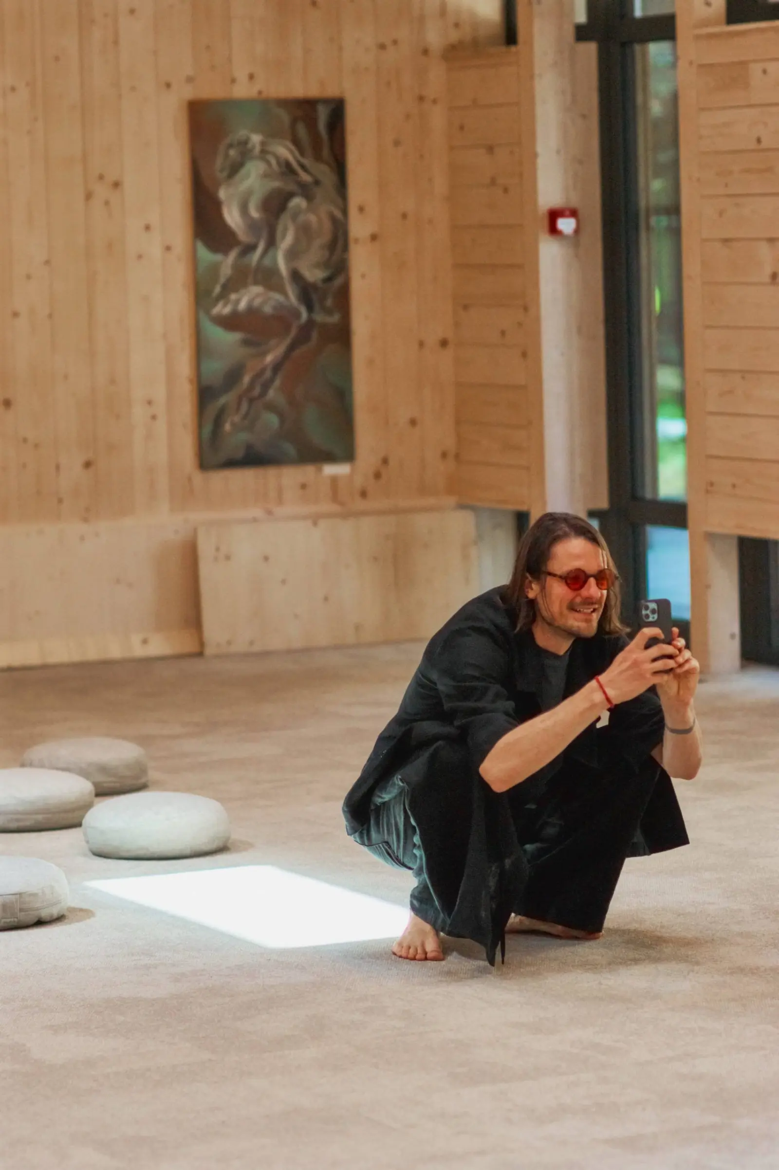 A speaker crouching beside a timber column at Nuoramos