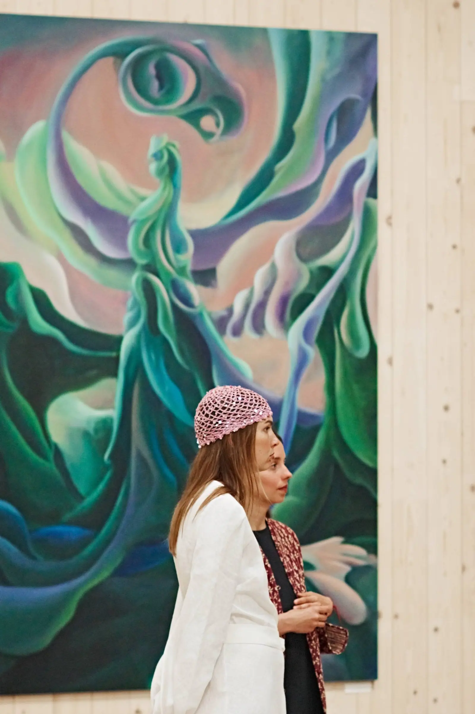 Visitors beside a green figurative painting at Nuoramos
