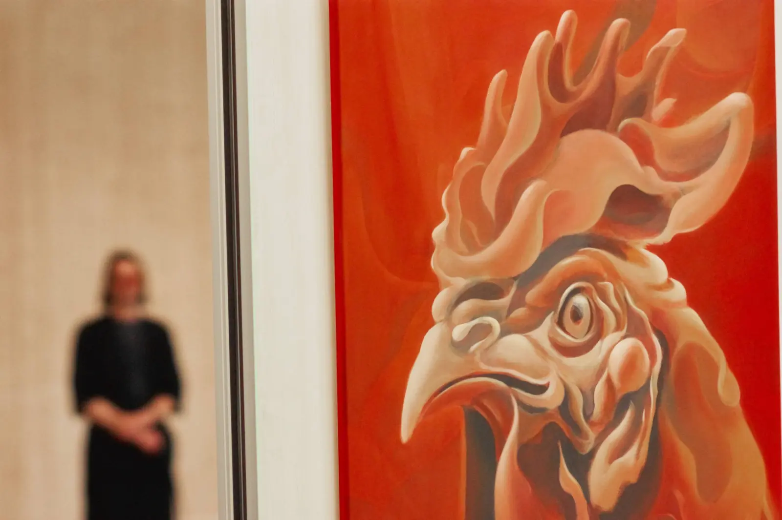 Close view of an orange painting with a visitor beyond it at Nuoramos