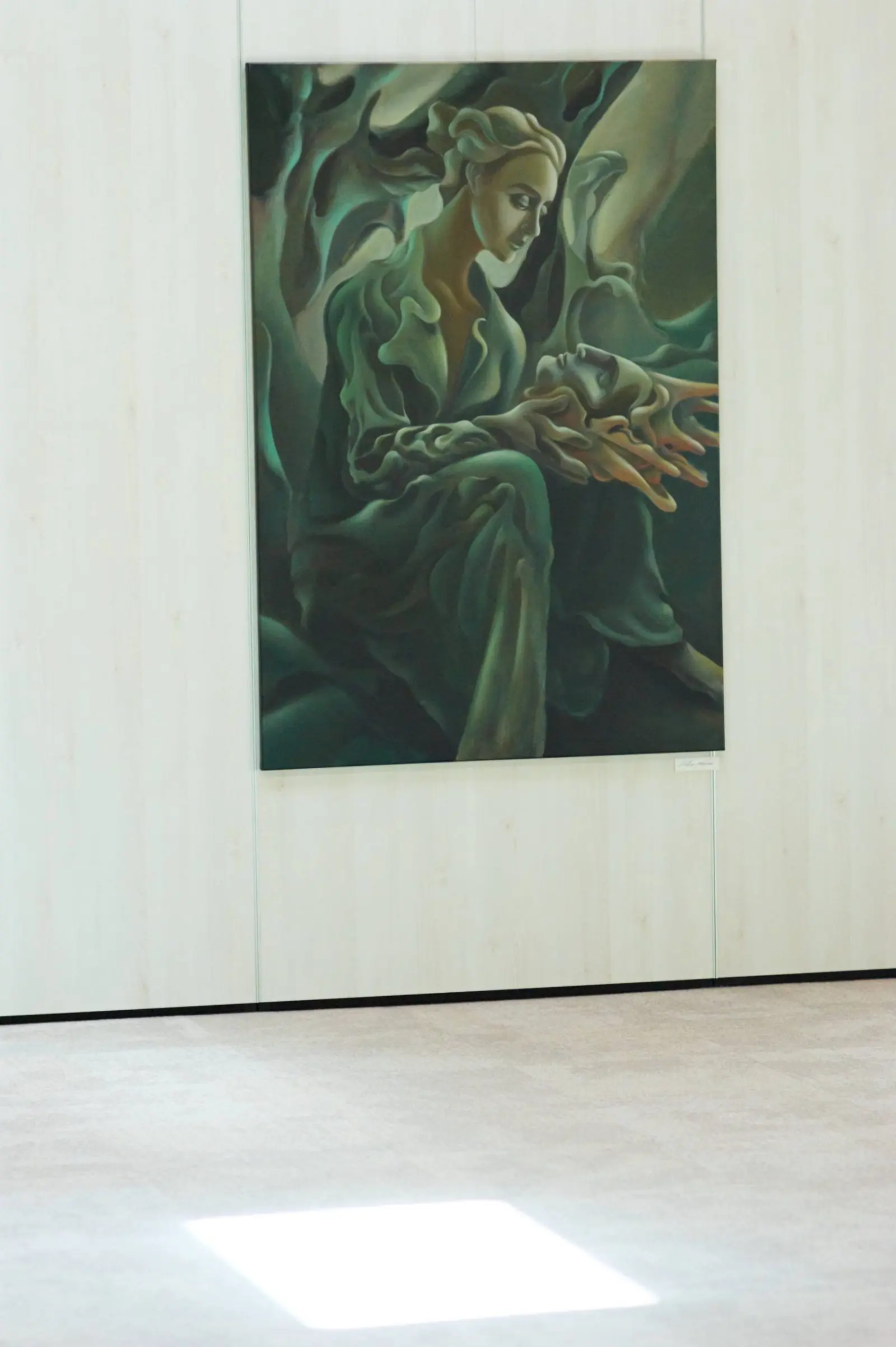 A green painting displayed against timber panels at Nuoramos