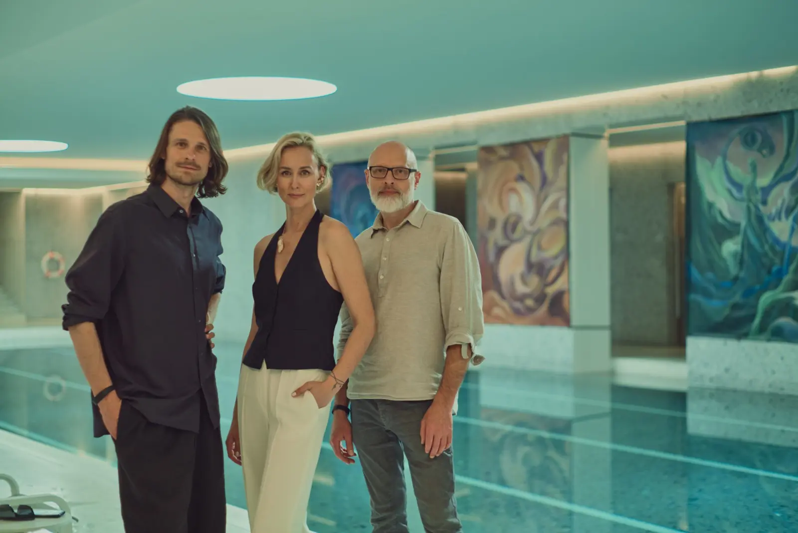 Three people standing beside the pool and paintings at Water Body
